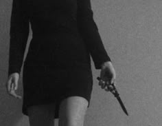 a woman holding a pair of scissors in her right hand while standing against a wall