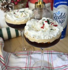 two glasses filled with dessert sitting on top of a table