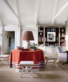 a living room filled with furniture and a red table cloth on top of a wooden floor