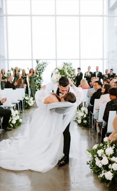 a bride and groom hug as they walk down the aisle in front of an audience