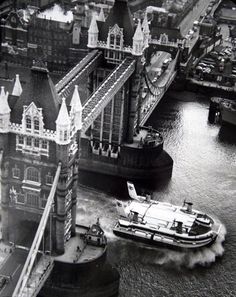 an aerial view of the tower bridge in london with a speedboat passing under it