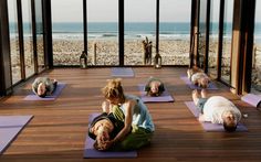 a group of people doing yoga on mats in front of an ocean view room with large windows