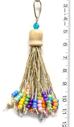 a wooden key chain with multi colored beads and a tassel hanging from it's end