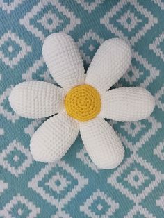 a crocheted flower laying on top of a blue and white blanket