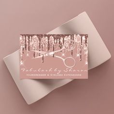 a pink business card with scissors and sequins on it, sitting on top of a white envelope