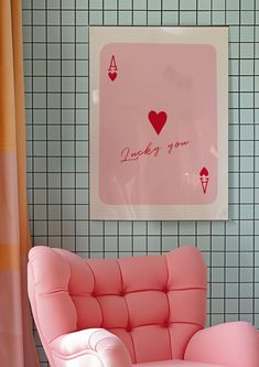 a pink chair sitting in front of a wall with a heart on it's back