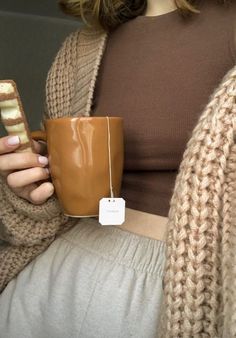 a woman holding a coffee cup and cell phone