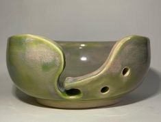 a green ceramic bowl with holes in the middle