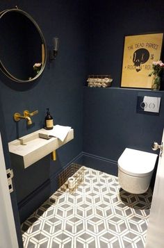 a white toilet sitting next to a sink in a bathroom under a mirror and a painting on the wall