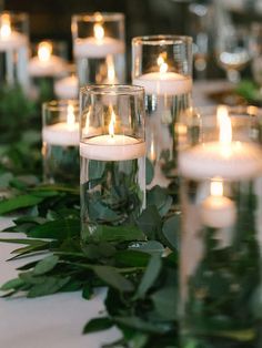 candles are lit on the table with greenery