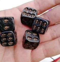 a hand holding five black dices with skulls on them