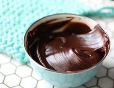 a blue bowl filled with chocolate frosting on top of a white tiled countertop