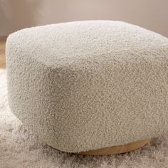 a large white ottoman sitting on top of a shaggy carpet covered floor next to a wall