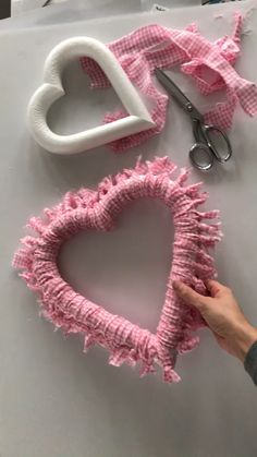 someone is making a heart shaped object out of yarn and fabric with scissors on the table