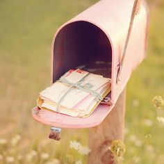 an old pink mailbox with papers sticking out of it