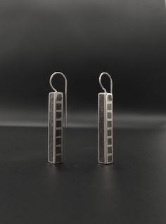 "These dangle geometric earrings have a horizontal rectangular shape, they are made of silver, the surface is hollow on the side has square gaps and the whole earring is covered with gray concrete, the finish is matte. These earrings are a trendy and special piece that can be worn with casual and formal outfits. It's perfect for making bold statements. DESCRIPTIONS and MEASUREMENTS: Material: Sterling Silver. Surface: Concrete  Dimensions : 3,5x0,5 (cm) 1,37x0,19 (in)\". thickness :0,5 (cm) 0,19 (in)\". Total Length :4,5 (cm) 1,77 (in)\". ΑLSO COMBINED WITH : www.etsy.com/shop/ArtisJewels?ref=seller-platform-mcnav&search_query=C5 Visit my Etsy shop, ArtisJewels, to see more earrings and jewelry and other unique handmade pieces. www.etsy.com/shop/ArtisJewels Do not hesitate to contact me fo Architectural Rings, Concrete Necklace, Tube Earrings, Concrete Ring, Architectural Jewelry, Gray Concrete, Concrete Pendant, Concrete Jewelry, Oxidized Silver Rings