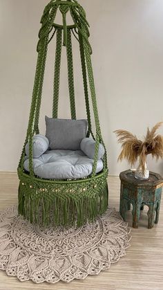 a swing chair made out of rope with pillows on the bottom and fringe around it