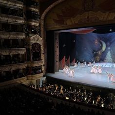 a group of people standing on top of a stage in front of an auditorium filled with people