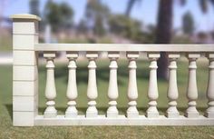 a close up of a white fence with grass and trees in the background