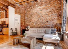 a living room filled with furniture and a brick wall