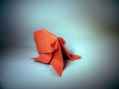 an orange origami bird sitting on top of a table