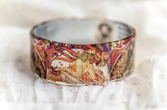 Resin Bangle, Art Jewelry, Alphonse Mucha Bracelet Alfons Maria Mucha (24 July 1860 - 14 July 1939) Middle design bangle - Height of the bangle - 3cm/1.18inches Mucha, was a Czech Art Nouveau painter and decorative artist,[3] known best for his distinct style. He produced many paintings, illustrations, advertisements, postcards, and designs.Alphonse Maria Mucha was born in the town of Ivančice, Moravia (currently a region of the Czech Republic). In 1871, Mucha became a chorister at the Cathedral Artistic Bangle Bracelet For Gift, Artistic Handmade Bangle As Gift, Hand Painted Wearable Art Bracelet As Gift, Artsy Bangle Jewelry For Gifts, Handmade Artistic Bangle As Gift, Artistic Adjustable Bangle As Gift, Artistic Handmade Bangle Bracelets, Artistic Hand-painted Bracelets As Gifts, Artistic Hand Painted Bracelets As Gift