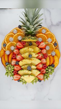 an arrangement of fruit arranged in the shape of a pineapple, oranges and strawberries