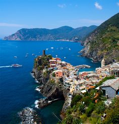 an aerial view of a small village on the edge of a cliff with boats in the water