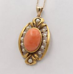 An Art Nouveau era angel skin coral and pearl pendant crafted in 14K gold with a rich bloomed finish. This piece was originally a brooch but now lives on as a wearable pendant. The center coral displays that soft pinkish orange color with some natural white graining and measures 14 mm long by 10 mm wide. Shimmery pearls are set around the coral. A lovely piece! Metal: 14K Yellow Gold (acid tested) Weight: 5 grams Coral: 14 mm long by 10 mm wide Measurement: 1.2 inches long (additional 0.25 inch Formal Coral Jewelry With Cabochon Details, Formal Coral Jewelry With Cabochon, Classic Coral Jewelry As Gift, Classic Coral Jewelry Gift, Vintage Coral Jewelry For Anniversary, Elegant Oval Coral Jewelry, Elegant Coral Oval Jewelry, Coral Vintage Jewelry For Anniversary, Elegant Coral Jewelry For Anniversary