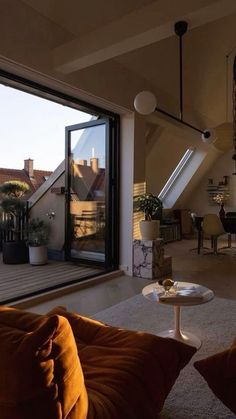 a living room filled with furniture next to an open roof top window overlooking the city