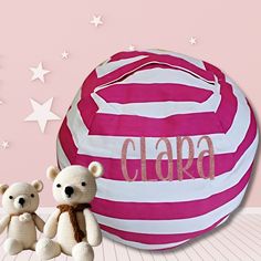 two teddy bears sitting next to a large pink ball with the word clara on it