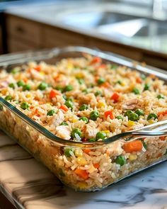 a casserole dish filled with rice, peas and carrots on a counter