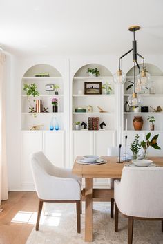 the dining room table is set with two white chairs, and there are bookshelves behind it