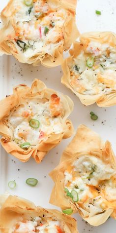 small shells filled with food sitting on top of a white plate next to green onions