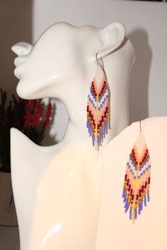 a pair of colorful beaded earrings sitting on top of a white mannequin