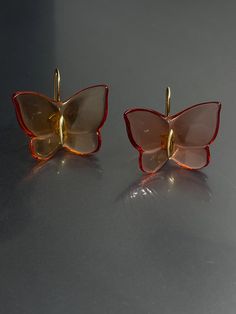 Elevate your style with these stunning Baccarat earrings. Crafted with yellow gold and amber tone crystal/glass, these earrings feature a beautiful butterfly design with a hook closure for easy wear. The dangle/drop style adds a touch of elegance to any outfit and the 1" length is perfect for the lobe area. These earrings are signed by Baccarat and boast a unique combination of beauty, nature, art, animals & insects, bohemian, and fashion & costumes themes. The crystal/glass material adds a spar Luxury Clear Earrings For Formal Events, Gold Butterfly Earrings For Formal Occasions, Luxury Gold Butterfly Earrings, Luxury Amber Drop Earrings, Luxury Yellow Gold Butterfly Earrings, Orange Pierced Earrings For Formal Occasions, Formal Orange Pierced Earrings, Orange Clip-on Earrings For Formal Occasions, Orange Formal Earrings