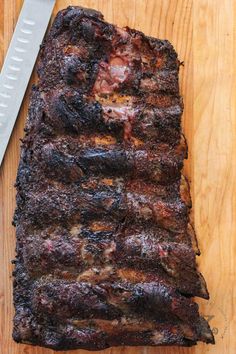 a piece of meat sitting on top of a wooden cutting board next to a knife