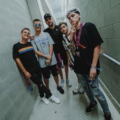 a group of young men standing next to each other in a hallway with grey walls