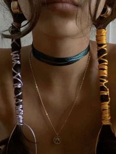 a woman with long hair wearing three necklaces on her neck and two earrings on her chest