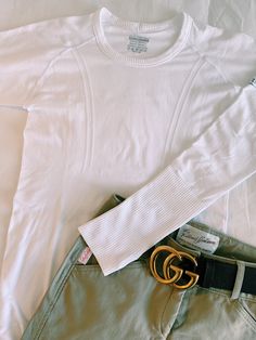 a white sweater and belt laying on top of a bed next to some pants with the label gucci