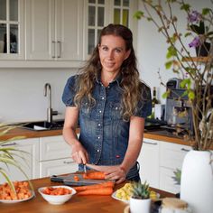 a woman is cutting carrots in the kitchen with other foods on the counter top