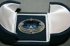 RARE!!  BEAUTIFUL VICTORIAN STYLE OVAL BROOCH WITH BLUE COLORED SYNTHETIC STONE, FACETED WITH A SILVER TONE EDGE. THE BROOCH HAS AN OPEN BACK AND IS FACETED AT THE LOWER PART TO PROJECT AS MUCH LIGHT AS POSSIBLE THROUGH THE BROOCH. IT IS IN EXCELLENT CONDITION, WITHOUT SCRATCHES AND HAS A WORKING C-CLASP ON THE BACK. A GOOD SOLID PERIOD BROOCH. DIMENSION: 4 CM. X 2.5 CM. 1 CM HIGH. WEIGHT 13 GRAMS Every collector would like it among his articles. Make sure you have read the descriptions carefull Blue Oval Brooch Jewelry, Blue Oval Brooch For Gifts, Oval Blue Brooch Jewelry, Oval Blue Brooch, Formal Blue Gemstone Brooch, Formal Blue Gemstone Brooches, Blue Oval Brooch, Elegant Blue Oval Brooches, Blue Gemstone Brooch For Anniversary