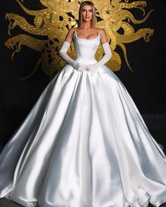 a woman in a white wedding dress standing next to a golden dragon on a black background