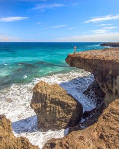 a man standing on top of a cliff next to the ocean