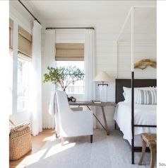 a bedroom with white bedding and curtains