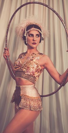 a woman is posing with a hoop around her waist and wearing an elaborate headdress