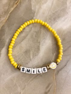 a yellow beaded bracelet with the word smile on it