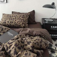 a leopard print comforter on a bed next to a lamp and other items in front of it