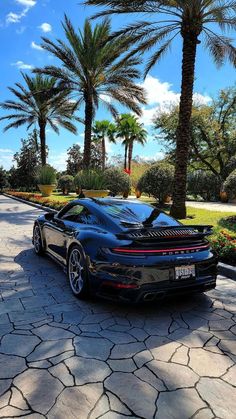 a black sports car parked on the side of a road with palm trees in the background