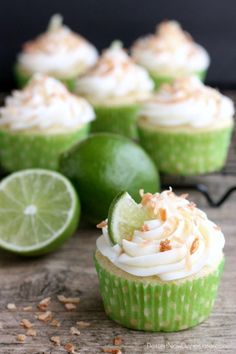 lime cupcakes with white frosting and toasted coconut on wooden table next to lime